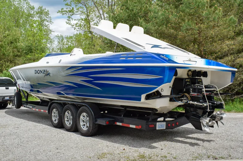 Slide: The Image of 2005 Donzi 38 ZR speedboat on trailer, featuring sleek blue and white design. - 2