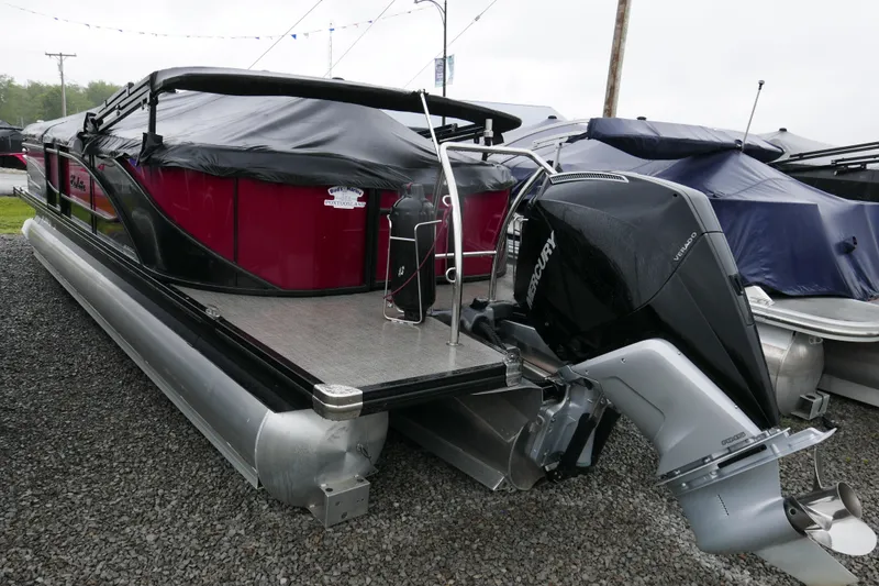 Slide: The Image of 2022 Barletta CORSA 23QC pontoon boat with Mercury outboard motor, covered and parked on gravel. - 14