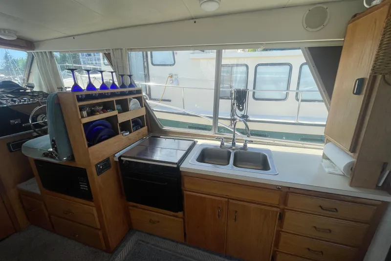 Slide: The Image of 1974 Tollycraft 37 Sedan interior with kitchen sink, stove, and glassware storage. - 17