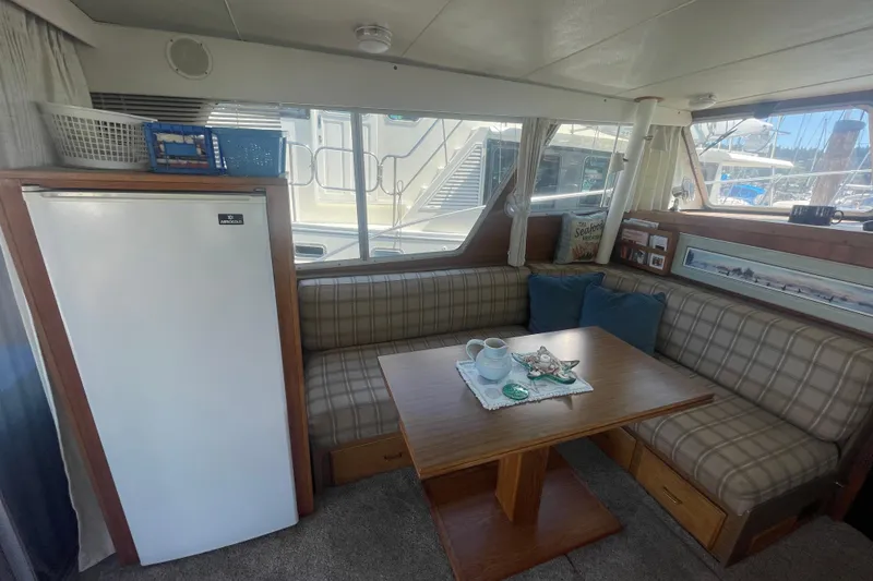 Slide: The Image of 1974 Tollycraft 37 Sedan interior with plaid seating, wooden table, and refrigerator. - 19