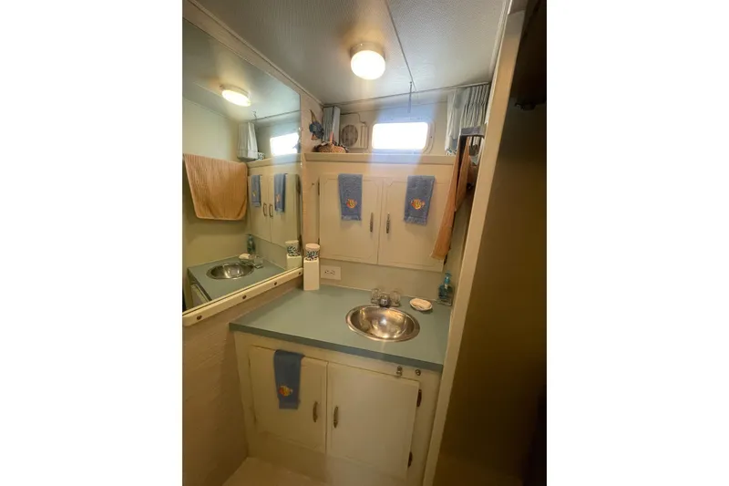 Slide: The Image of 1974 Tollycraft 37 Sedan bathroom with sink, mirror, and storage cabinets. - 38