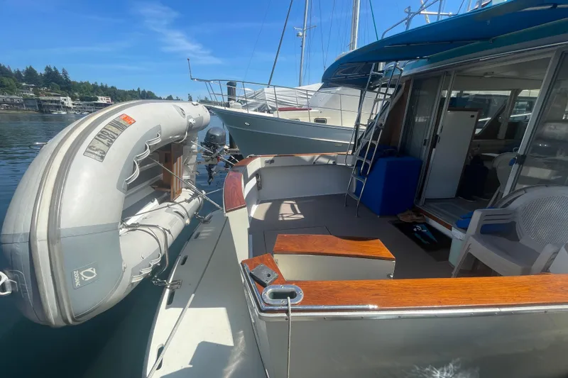 Slide: The Image of 1974 Tollycraft 37 Sedan yacht with inflatable dinghy, docked in a serene marina setting. - 9