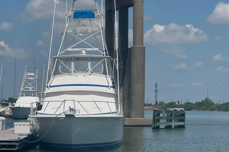 Slide: The Image of Bertram 54 Convertible yacht docked by a bridge, clear sky, 1997 model. - 1