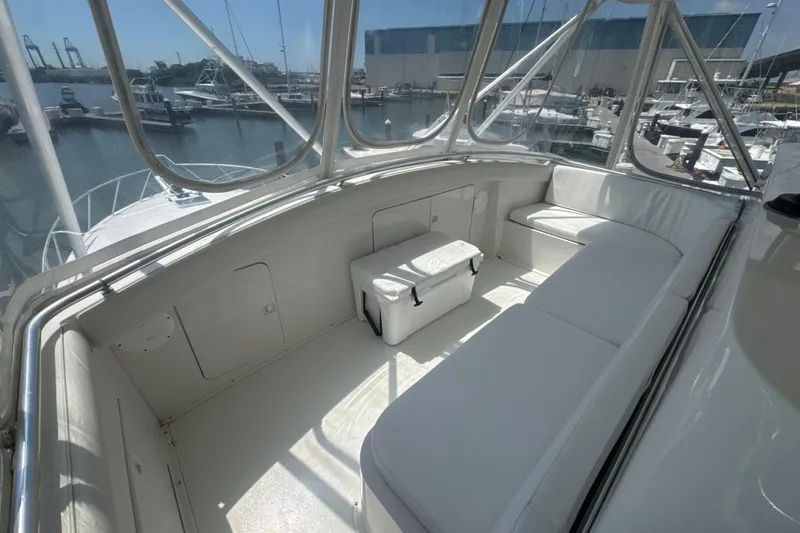 Slide: The Image of 1997 Bertram 54 Convertible yacht interior with white seating and marina view. - 11