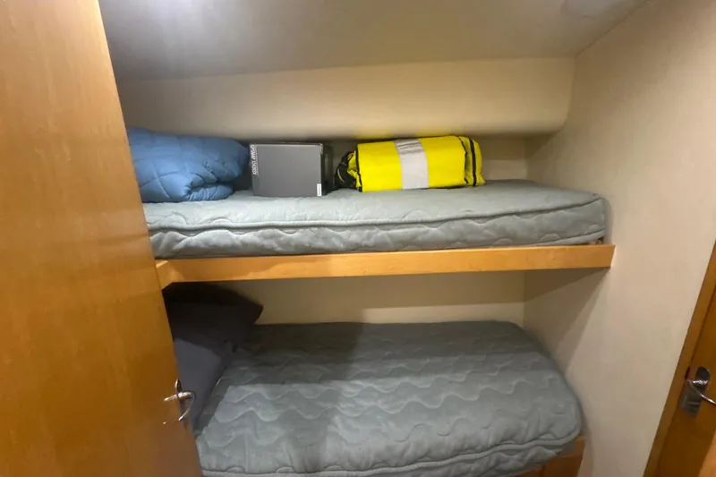 Slide: The Image of Bunk beds in a 1997 Bertram 54 Convertible yacht cabin, featuring cozy bedding and storage. - 25