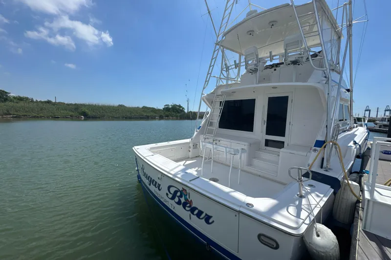 Slide: The Image of 1997 Bertram 54 Convertible yacht docked on a sunny day, featuring spacious deck and fishing equipment. - 5