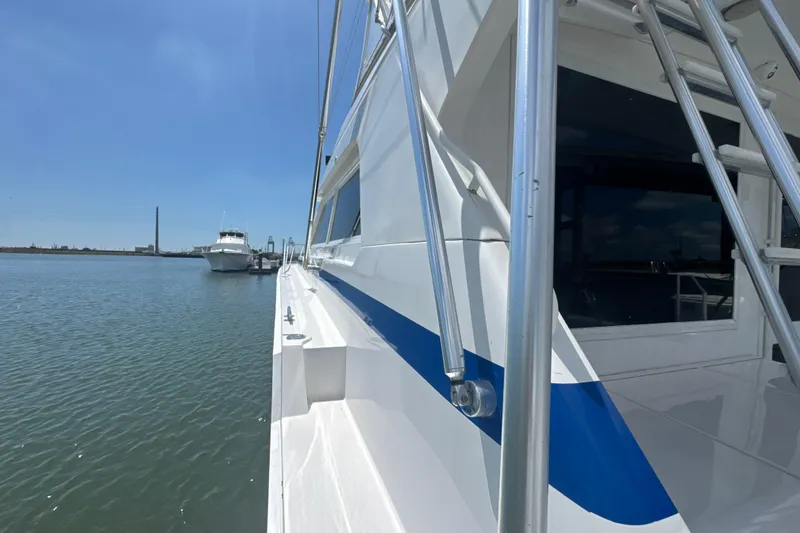 Slide: The Image of 1997 Bertram 54 Convertible yacht docked on calm water under clear blue sky. - 7
