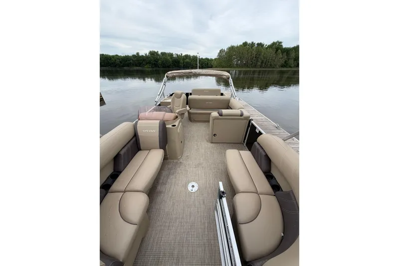 Slide: The Image of 2022 Sylvan Mirage 8522 Resorter pontoon boat interior with beige seating on a calm lake. - 7
