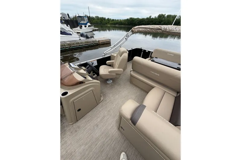Slide: The Image of 2022 Sylvan Mirage 8522 Resorter pontoon boat interior with beige seating and helm. - 9