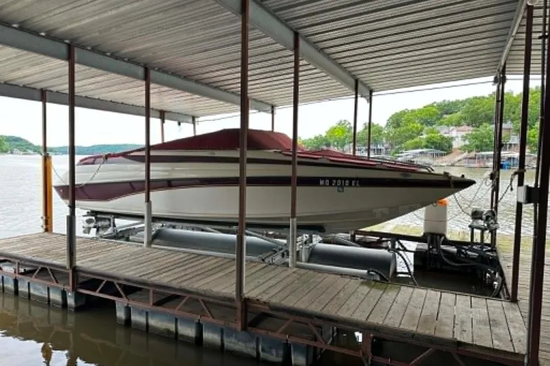 The Image of 1998 Crownline 248 BR boat docked under a covered marina on a lake. - 0