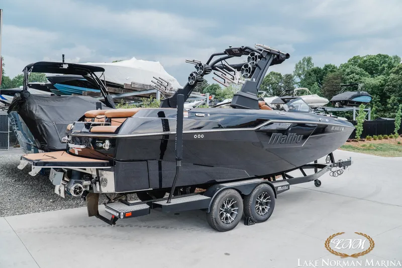 Slide: The Image of 2021 Malibu M240 boat on trailer at Lake Norman Marina, showcasing sleek design and modern features. - 2