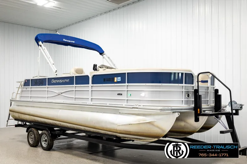 Slide: The Image of 2019 Berkshire 24 SB2 CTS pontoon boat with blue canopy on trailer in indoor storage. - 2