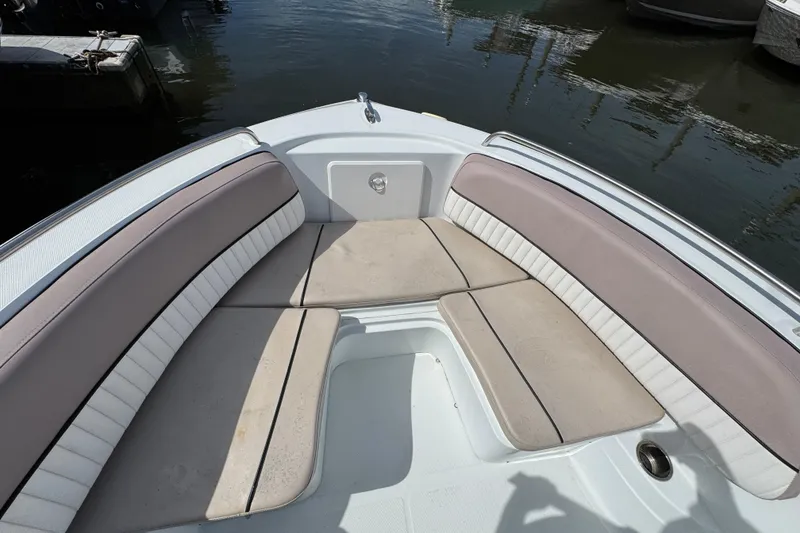 Slide: The Image of 2022 Barracuda 188 CCR boat interior with cushioned seating, docked on calm water. - 14