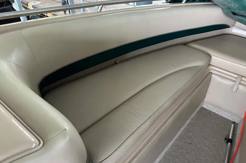 Slide: The Image of Interior seating of a 1997 Crownline 225 BR boat, featuring beige upholstery. - 9