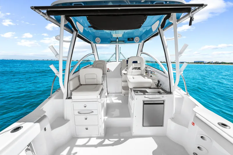 Slide: The Image of The image shows the cockpit of a 2027 Boston Whaler 285 Conquest. It features white seating and a blue canopy, surrounded by clear blue water. - 28