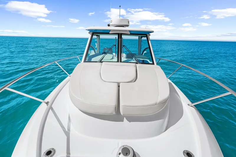 Slide: The Image of The 2027 Boston Whaler 285 Conquest cruises on calm, blue waters under a clear sky. - 40