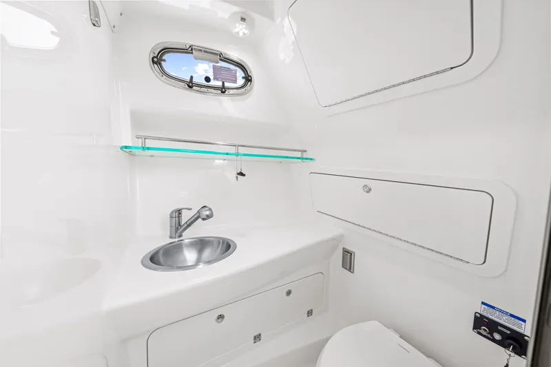 Slide: The Image of The image shows the bathroom of a Boston Whaler 285 Conquest. It features a modern, clean design with a sink, small window, and storage. - 48