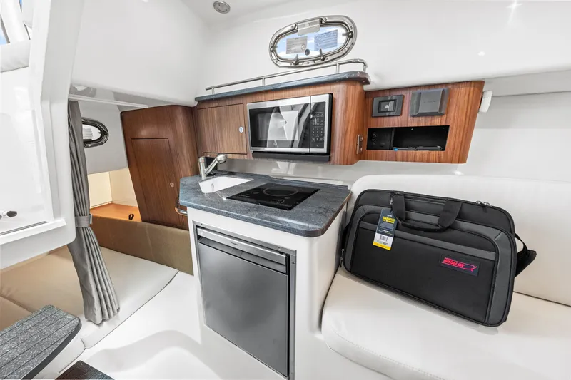 Slide: The Image of The cabin of the 2027 Boston Whaler 285 Conquest features a compact kitchen with a microwave and sink. - 47