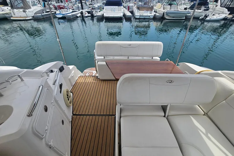 Slide: The Image of 2009 Regal 2860 Window Express boat interior with white seating and wooden deck at marina. - 10