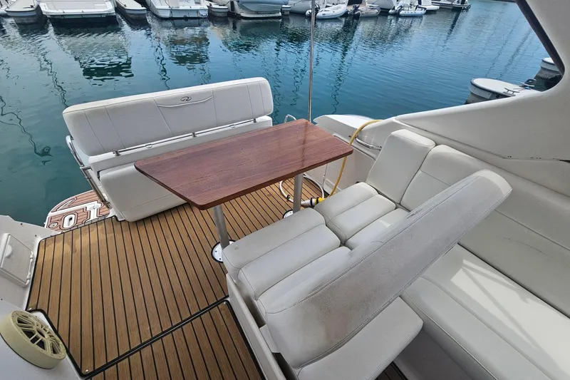 Slide: The Image of 2009 Regal 2860 Window Express boat interior with white seating and wooden table at marina. - 12