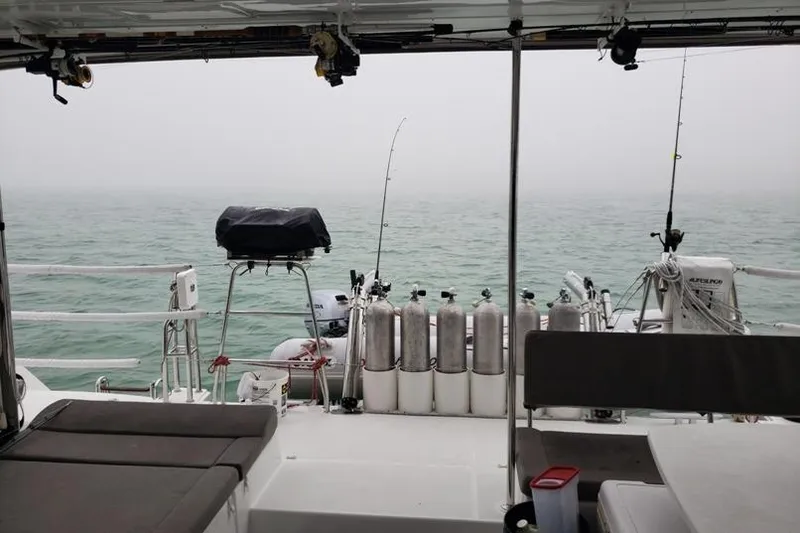 Slide: The Image of Lagoon 450 F catamaran deck with fishing rods and scuba tanks, 2016 model, on a misty sea. - 3