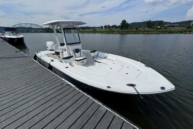Slide: The Image of 2023 Robalo 246 Cayman boat docked on a calm river with scenic background. - 1
