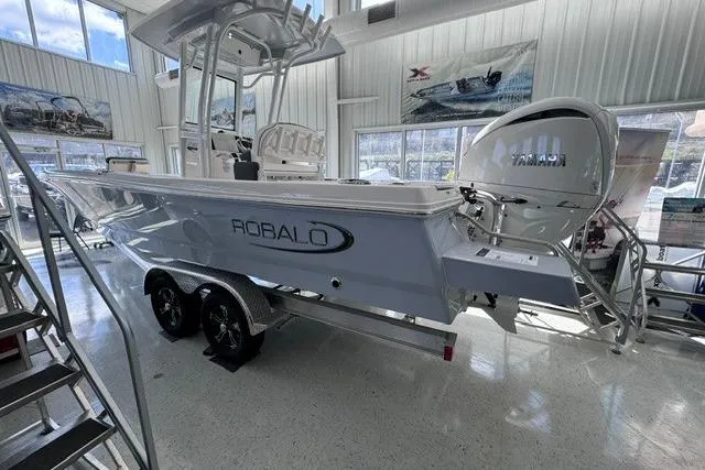 Slide: The Image of 2023 Robalo 246 Cayman boat displayed indoors on a trailer. - 3