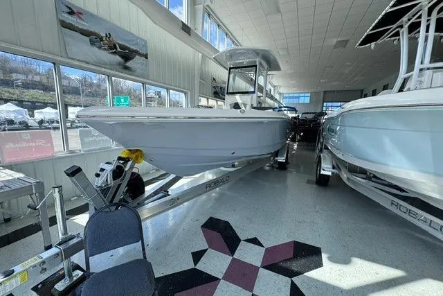 Slide: The Image of 2023 Robalo 246 Cayman boat displayed indoors on a trailer. - 4
