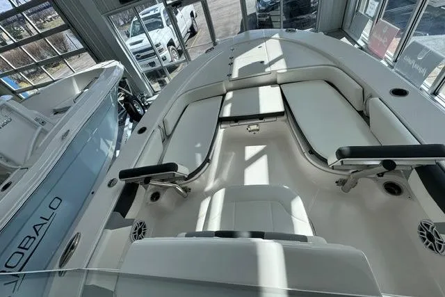 Slide: The Image of 2023 Robalo 246 Cayman boat interior with cushioned seating in showroom. - 5
