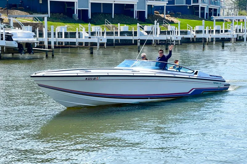 The Image of 1991 Formula 311 SR-1 boat cruising on a sunny day near docks. - 1