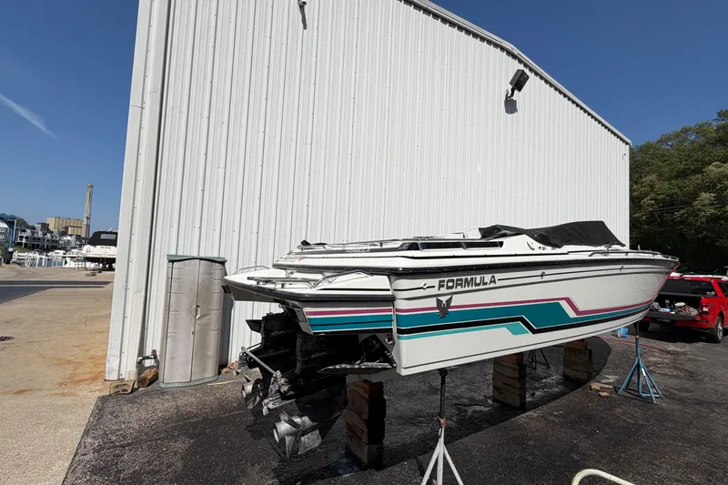 Slide: The Image of 1991 Formula 311 SR-1 boat on stands, white with colorful stripes, near a large building. - 8