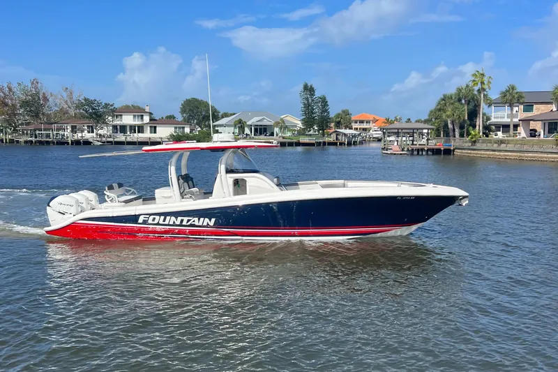 The Image of 2021 Fountain 39 NX boat cruising on a sunny day near waterfront homes. - 0