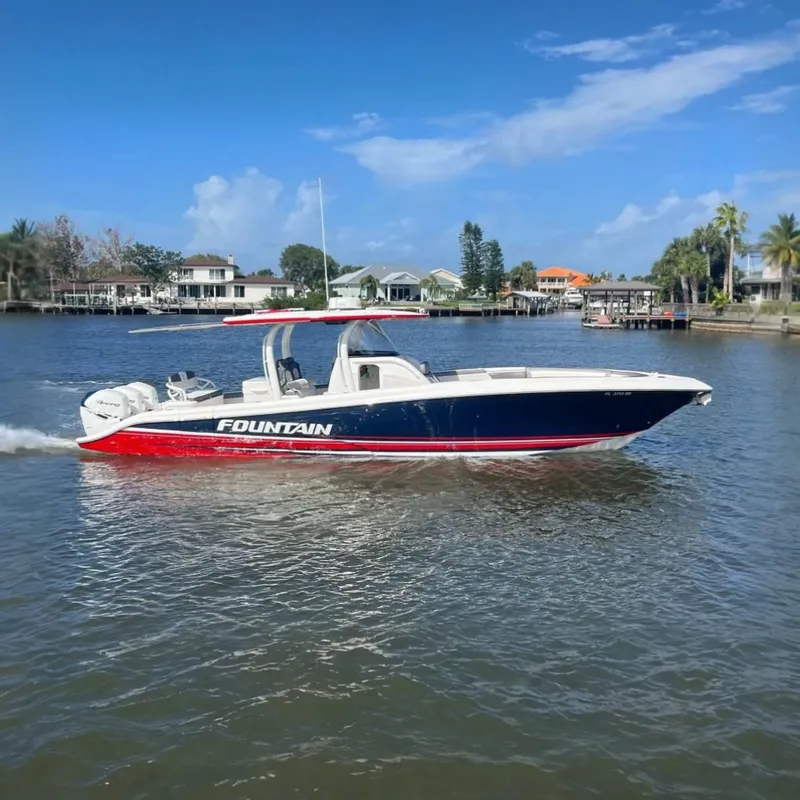 The Image of 2021 Fountain 39 NX boat cruising on a sunny day near waterfront homes. - 0