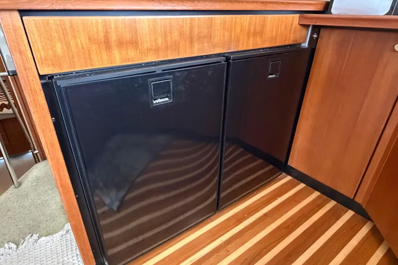 Slide: The Image of 1996 Bayliner 3988 Command Bridge Motoryacht interior with dual black refrigerators and wood paneling. - 33