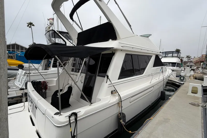 Slide: The Image of 1996 Bayliner 3988 Command Bridge Motoryacht docked at marina, featuring sleek design and black canopy. - 4