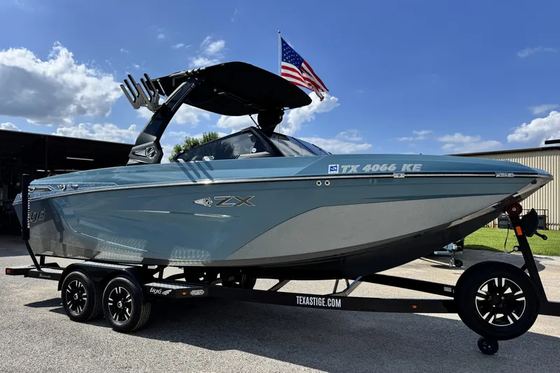 The Image of 2021 Tigé 23ZX boat on trailer with American flag, under blue sky. - 1
