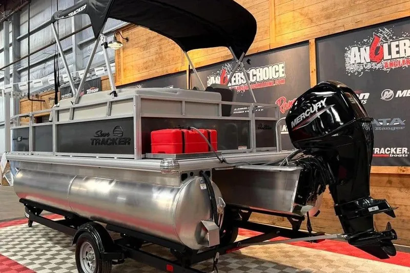 Slide: The Image of 2026 Sun Tracker Bass Buggy 16 XL Select pontoon boat with Mercury outboard motor in showroom. - 5