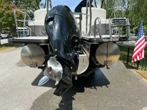 Slide: The Image of 2024 Harris CX 230 pontoon boat with outboard motor and US flag. - 2
