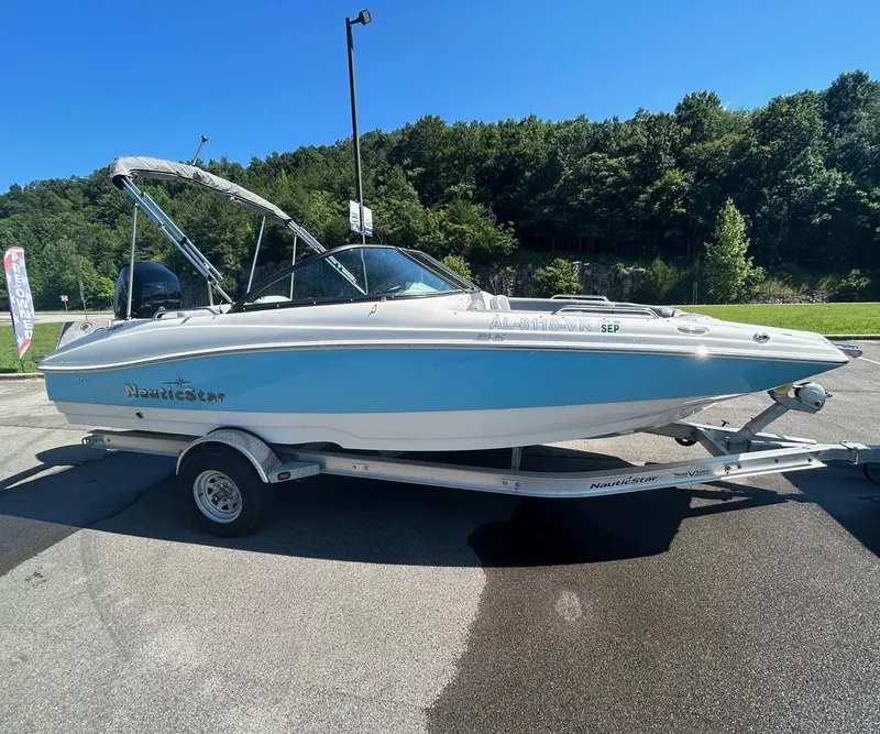 The Image of 2022 NauticStar 203 DC boat on trailer, blue hull, sunny day. - 1