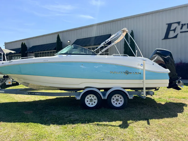The Image of 2024 NauticStar 223 DC boat on trailer in front of building. - 1