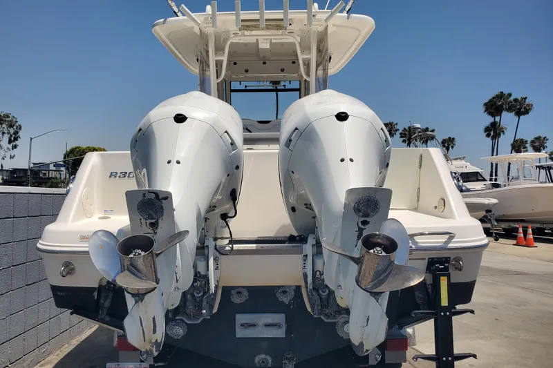 Slide: The Image of 2017 Robalo R302 Center Console boat with dual outboard engines, docked under clear skies. - 11