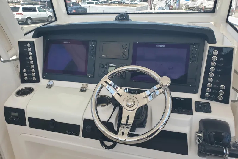 Slide: The Image of 2017 Robalo R302 Center Console helm with dual Simrad displays and steering wheel. - 14