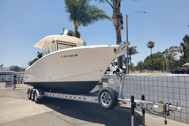 Slide: The Image of 2017 Robalo R302 Center Console boat on trailer, parked outdoors under clear sky. - 2