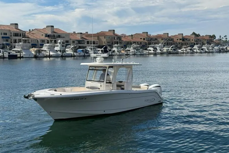 Slide: The Image of 2017 Robalo R302 Center Console boat on calm water near marina with docked yachts. - 5