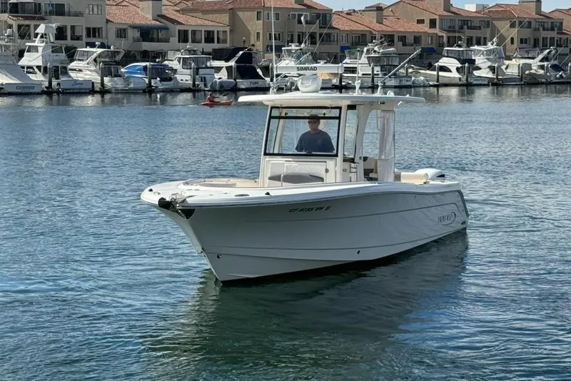 Slide: The Image of 2017 Robalo R302 Center Console boat cruising in a marina with docked yachts. - 6
