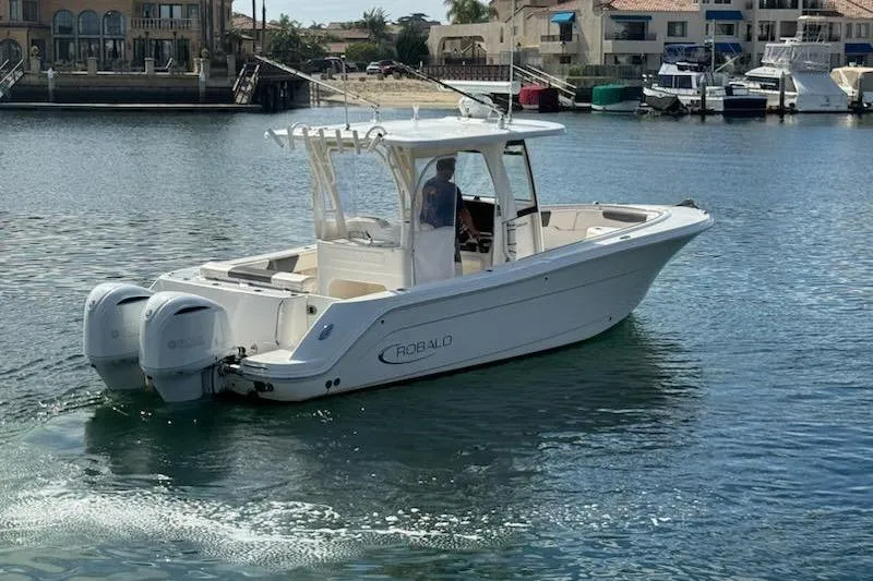 Slide: The Image of 2017 Robalo R302 Center Console boat cruising in a marina with dual engines. - 7