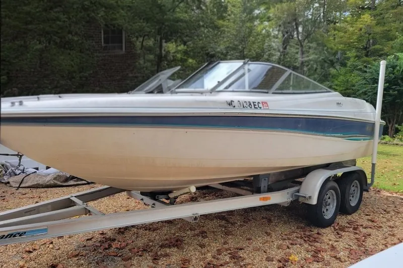 The Image of 1999 Wellcraft 186 SS/S boat on trailer, parked outdoors in a wooded area. - 1