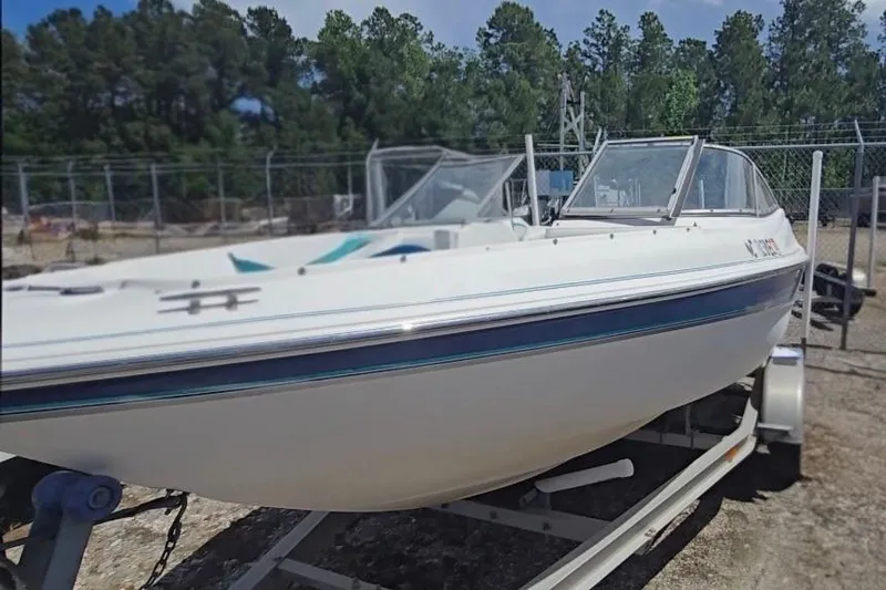 Slide: The Image of 1999 Wellcraft 186 SS/S boat on trailer, parked outdoors near trees and fencing. - 4