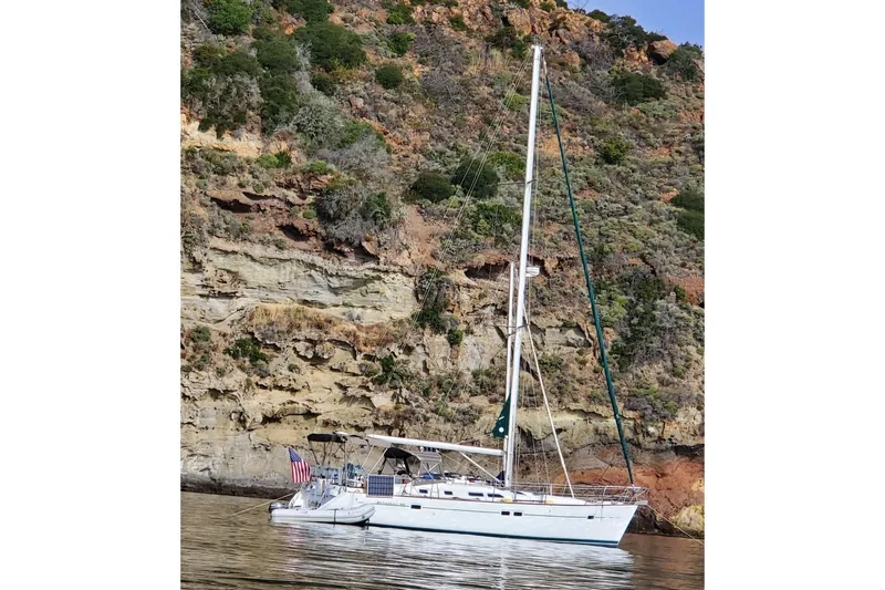The Image of 2003 Beneteau 423 sailboat anchored near rocky cliffside, displaying American flag. - 0