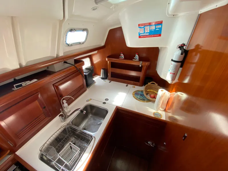Slide: The Image of Galley kitchen in 2003 Beneteau 423 sailboat with wooden cabinetry and stainless steel sink. - 41